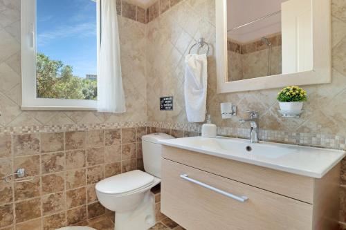 a bathroom with a toilet and a sink and a window at Villa Belvedere Rosa in Tsoukaladhes
