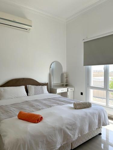 Dormitorio blanco con cama grande y almohada naranja en VILLA seeb 2 MIN walk to the beach, en Seeb