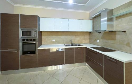 a large kitchen with wooden cabinets and a sink at H-Apartment Lungo Mare in Vlorë