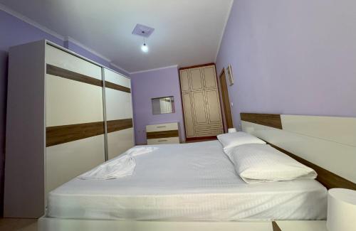 a bedroom with a large white bed with purple walls at H-Apartment Lungo Mare in Vlorë