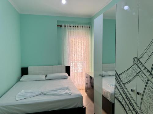a blue bedroom with a bed with a bow on it at H-Apartment Lungo Mare in Vlorë