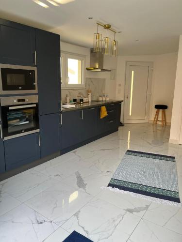 Il comprend une cuisine avec des placards bleus et du carrelage blanc. dans l'établissement Location Studio Luxe Villejuif, à Villejuif