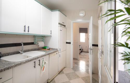a kitchen with white cabinets and a sink at Mar y montaña in Monachil