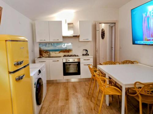 uma cozinha com uma mesa e um frigorífico amarelo em La Grotta em Urzulei