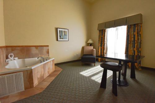La salle de bains est pourvue d'une baignoire, d'un tabouret et d'une chaise. dans l'établissement Holiday Inn Express & Suites Cocoa, an IHG Hotel, à Cocoa