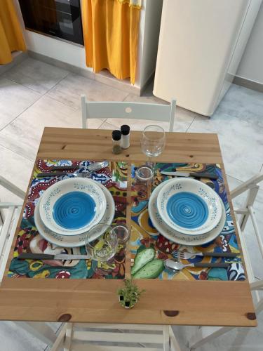 a table with two plates and wine glasses on it at Rossaroll Holiday Houses in Noto