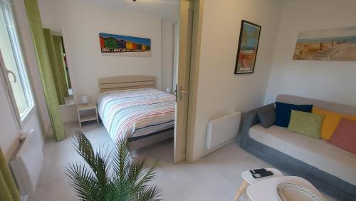 a small room with a bed and a couch at T2, 50m du lac, PISCINE, WIFI, jardin terrasse sans vis-à-vis, 1 à 4 pers in Aureilhan