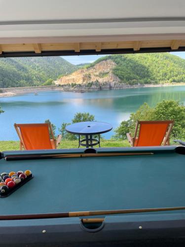 a pool table with two chairs and a view of a lake at Zoranovi konaci in Jevtići