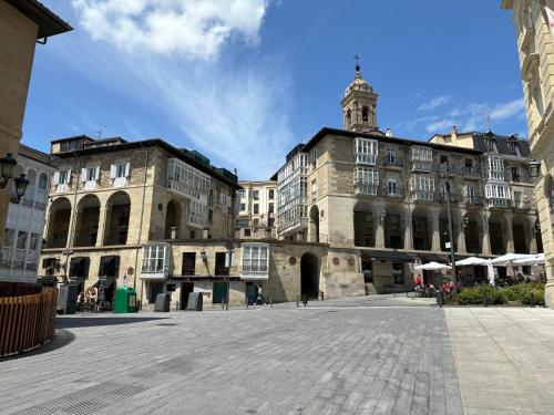 un grand bâtiment avec une tour d'horloge dans une cour dans l'établissement Luxury Arquillos Vitoria, à Vitoria-Gasteiz