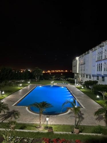 a large blue pool in front of a building at night at Achakar complexe payasage del costa in Jbila