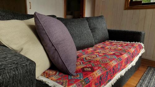 Un sofá con dos almohadas y una manta. en Tres Bosques en Pucón