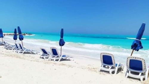 a group of chairs and umbrellas on a beach at استديو فندقى مكيف بتراس اكوا فيو Aquaview in El Alamein