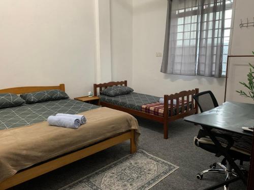 a room with two beds and a desk and a table at La wood homestay in Kuala Besut