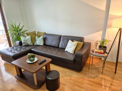a brown leather couch in a living room with a table at Amsterdam Apartment Strumica in Strumica