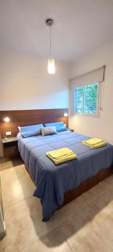 Un dormitorio con una gran cama azul con toallas amarillas. en Dpto 1 dormitorio a 2 cuadras de Parque de Mayo, en San Juan