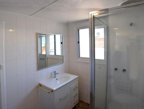 a white bathroom with a sink and a shower at The Palace Hotel Kalgoorlie in Kalgoorlie