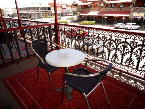a patio area with chairs, tables, and a balcony at The Palace Hotel Kalgoorlie in Kalgoorlie