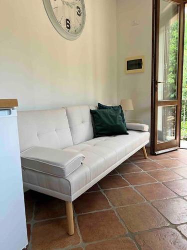 a white couch in a living room with a clock on the wall at iL VICOLO NEL VERDE in Rio Marina