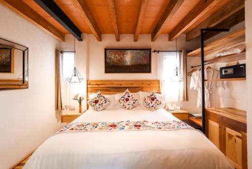 una camera da letto con un grande letto bianco con cuscini di Mesón De Leyendas Breakfast & Downtown a Valle de Bravo