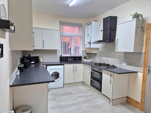 una cucina con mobili bianchi, lavatrice e asciugatrice di Rooms in Manchester 6 minutes Drive to Victoria Station a Manchester