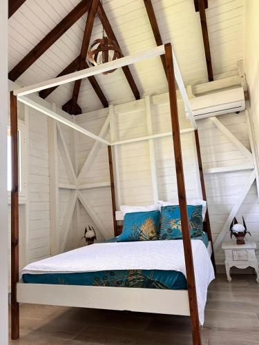 1 dormitorio con cama con dosel y almohadas azules en gîte de forêt de Guadeloupe, en Petit-Bourg