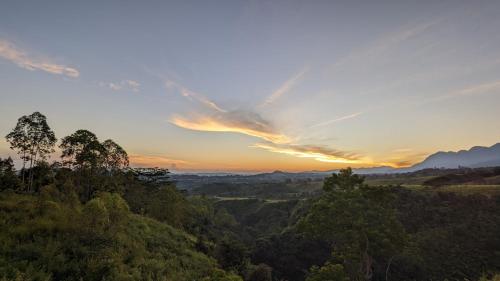 a sunset over a forested area with trees at Ruteng Glamping & Campsite in Ruteng