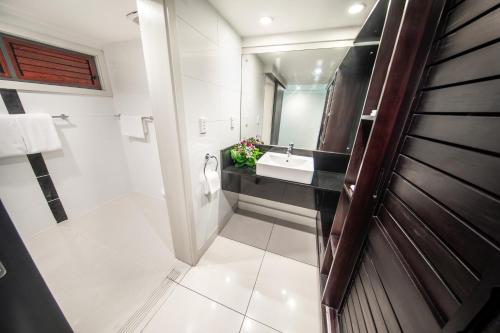 uma casa de banho com um lavatório e um espelho em Tanoa Tusitala Hotel em Apia