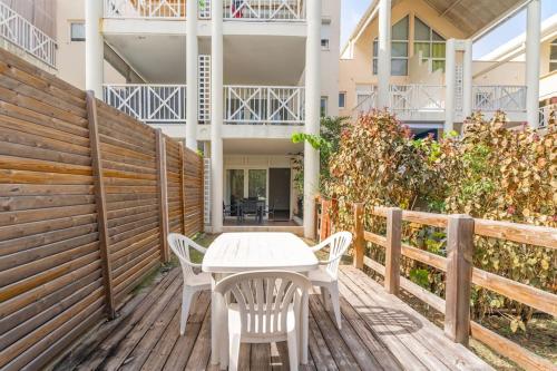 Un patio con una mesa y sillas en una terraza de madera. en Appartement Macaron Clair, en Le Diamant