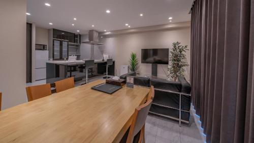 a living room with a large wooden table and a kitchen at Residence Hotel Takayama Station in Takayama