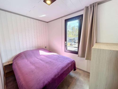 une chambre avec un lit violet et une fenêtre dans l'établissement Chalet 6 Pers. à Jullouville - Piscine Chauffée, Proche Plage et Commerces - FR-1-361-541, à Saint-Pair-sur-Mer
