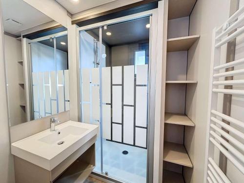 une salle de bain avec un lavabo et une douche en verre dans l'établissement Chalet 6 Pers. à Jullouville - Piscine Chauffée, Proche Plage et Commerces - FR-1-361-541, à Saint-Pair-sur-Mer