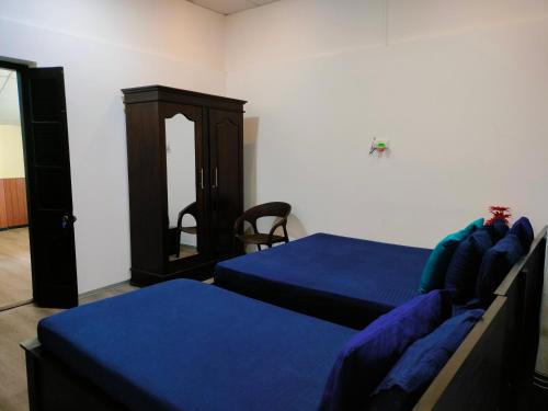 a bedroom with two beds with blue sheets and a cabinet at Taj Residence in Puttalam