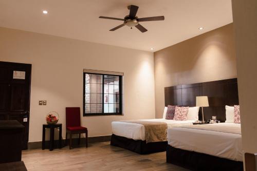 Punto Madero Hotel & Plaza في Mocorito: غرفة فندقية بسريرين ومروحة سقف