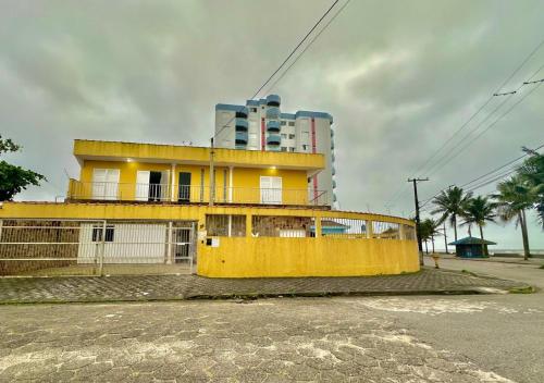 un edificio amarillo frente a un edificio alto en Hostel Encanto de Mongaguá, en Mongaguá