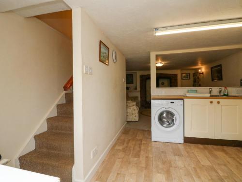 eine Waschküche mit einer Waschmaschine und einer Treppe in der Unterkunft The Cottage in Bideford