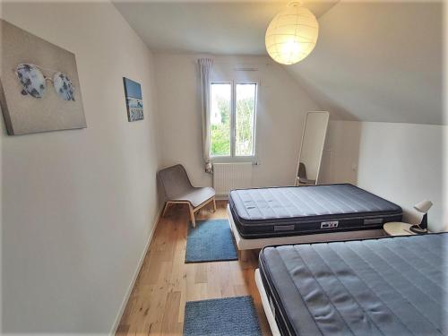 une chambre avec deux lits et une chaise et une fenêtre dans l'établissement Maison 8 pers, proche plage et commerces, jardin, barbecue, équipements bébé, linge inclus - FR-1-639-122, à Arzon