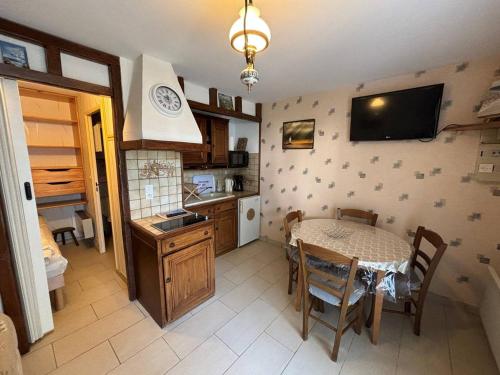 une cuisine et une salle à manger avec une table et une télévision dans l'établissement Rez-de-jardin avec accès direct à la plage, terrasse ensoleillée, idéal pour 3 personnes - FR-1-465-115, à Merville-Franceville-Plage