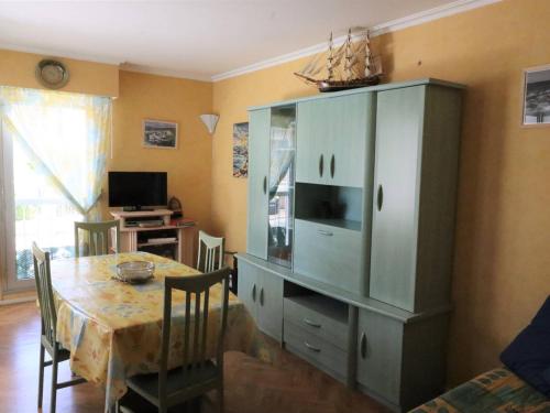 une salle à manger avec une table et un meuble vert dans l'établissement Appartement T2 à Royan - Plage de Pontaillac - 2 adultes/2 enfants, terrasses, parking, proche commerces - FR-1-738-32, à Royan