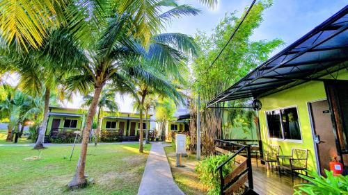 a house with a palm tree in front of it at Casa Fina Fine Homes in Pantai Cenang