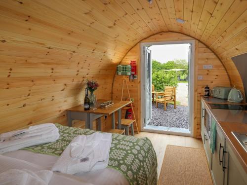 a bedroom in a log cabin with a bed and a kitchen at Moel Arthur in Denbigh