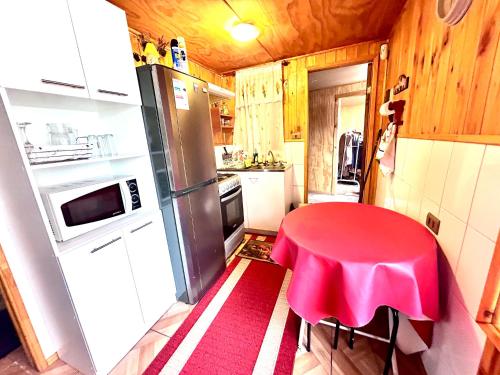 eine kleine Küche mit einem roten Tisch und einem Kühlschrank in der Unterkunft Cabañas Emma in Osorno