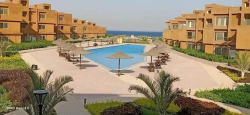 a swimming pool with umbrellas and chairs and buildings at Alsokhna gateway in Ain Sokhna