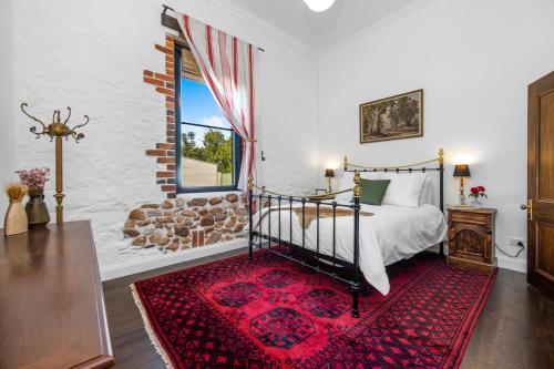 a bedroom with a bed and a window and a red rug at Arapiles Club House in Natimuk