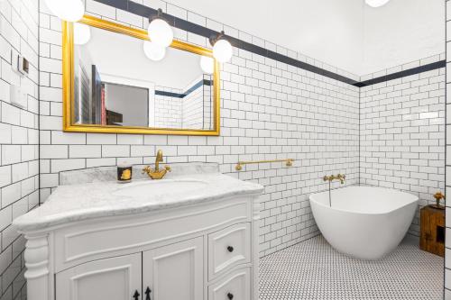 a bathroom with a sink and a tub and a mirror at Arapiles Club House in Natimuk