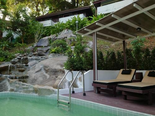 a patio with chairs and a pool of water at On The Hill Karon Resort in Karon Beach
