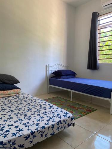 a bedroom with two beds and a window at Azfar Homestay in Kangar