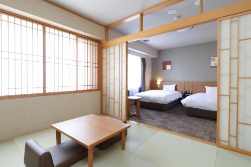 a hotel room with two beds and a table at Dormy Inn Chiba City Soga in Chiba