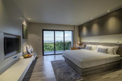 a bedroom with a large bed and a large window at Hotel IKON Phuket - SHA Extra Plus in Karon Beach