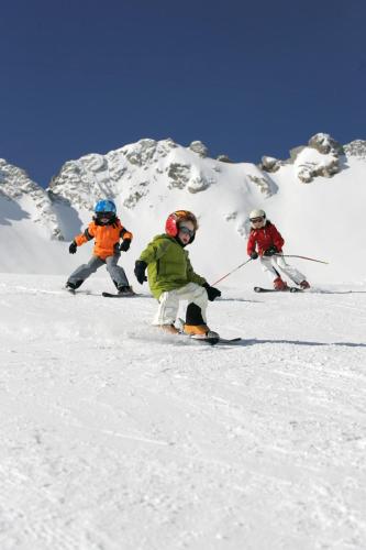 three people are skiing down a snow covered mountain at Gästehaus Bergstüberl in Reit im Winkl