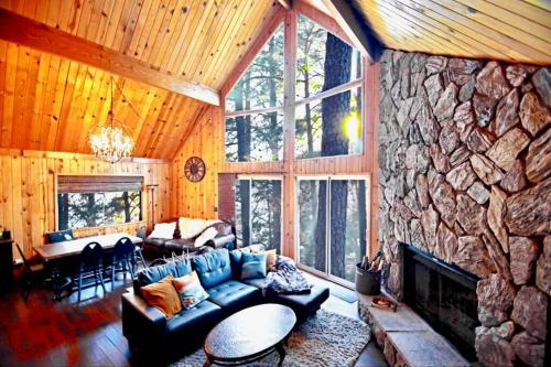 a living room with a blue couch and a stone fireplace at Glimmer Chalet Treetop A-frame cabin lake view in Lake Arrowhead